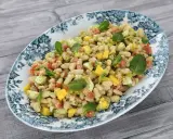 Deliciosa ensalada de alubias con trozos de tomate, mango y huevo, decorada con hojas de menta fresca.