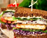 Delicioso sandwich vegetal con pan integral, tofu a la plancha, lechuga, tomate, cebolla morada y col lombarda.