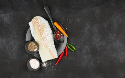 Filete de bacalao fresco listo para preparar a la brasa, con pimienta, sal y chiles.
