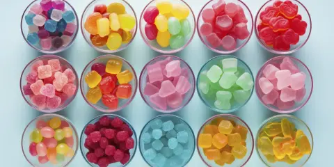 Cuencos llenos de gominolas caseras de colores vibrantes: azules, rosas, rojas, verdes, amarillas y naranjas.