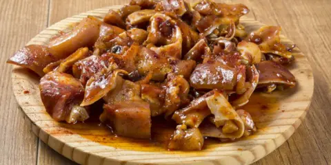 Oreja a la gallega, trozos de oreja de cerdo marinados y cocinados, servidos en una tabla de madera.