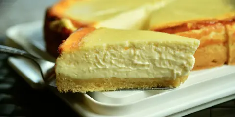 Una rebanada cremosa de tarta de queso Philadelphia, con su base dorada y relleno suave, lista para ser disfrutada.
