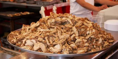 Montón de gallinejas y entresijos fritos, listos para servir en un puesto de comida callejera.