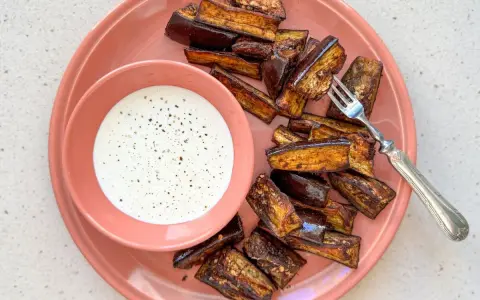 Berenjenas en freidora de aire, doradas y crujientes, servidas con una cremosa salsa blanca. ¡Un aperitivo delicioso!