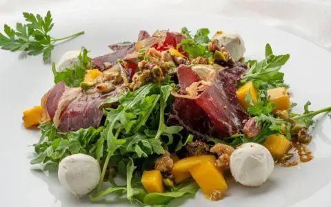 Deliciosa ensalada de cecina con mango, queso de cabra y nueces sobre rúcula fresca.
