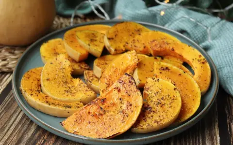 Rodajas de calabaza a la plancha, doradas y sazonadas con hierbas, servidas en un plato azul.