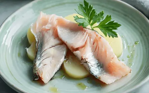 Lubina a la sal Thermomix: jugosos filetes de pescado sobre patatas, decorados con perejil fresco y un toque de aceite.