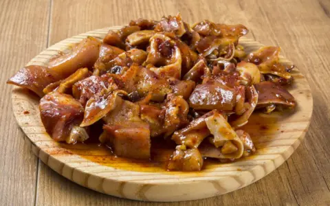 Oreja a la gallega, trozos de oreja de cerdo marinados y cocinados, servidos en una tabla de madera.
