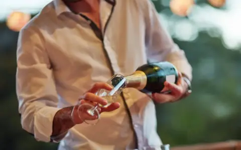 Un hombre sirve cava español en una copa.
