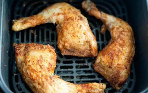 Muslos de pollo dorados y jugosos en la freidora de aire, listos para disfrutar.