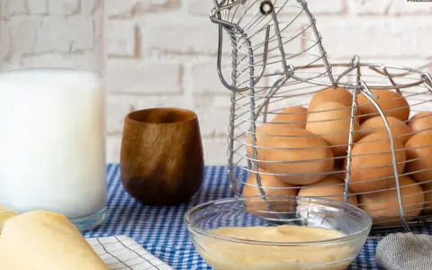 Crema pastelera lista para usar, hecha con Thermomix. Huevos frescos en cesta de gallina, leche y utensilios de repostería.