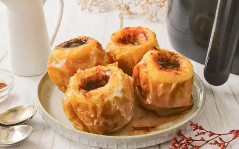 Cuatro manzanas asadas en freidora de aire, doradas y jugosas, con un relleno oscuro y especiado.