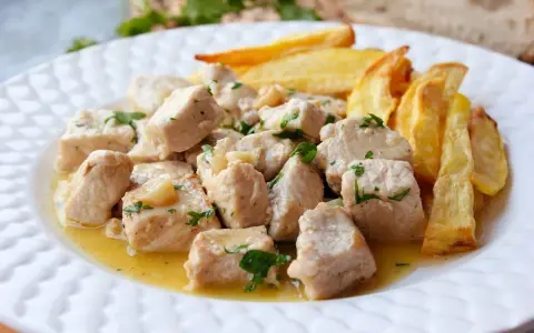 Sabroso lomo al ajillo en trozos, bañado en aceite y ajo, acompañado de patatas fritas crujientes.