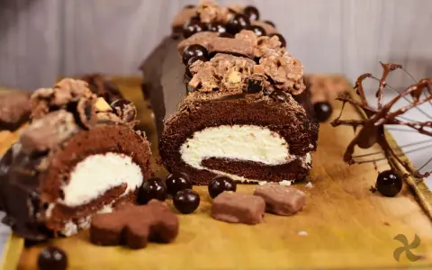 Delicioso rollo de chocolate cubierto con crema y decorado con más chocolate y dulces.