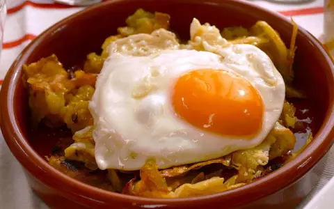 Un plato de patatas fritas con pimientos y un huevo estrellado encima, listo para disfrutar.