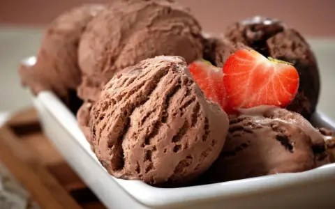 Cucharadas de cremoso helado de chocolate, decoradas con fresas frescas, listas para disfrutar.