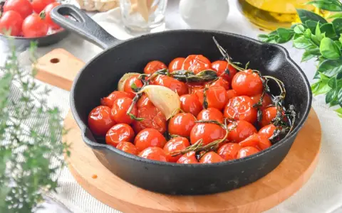 Tomates cherry confitados en sartén de hierro fundido, con ajo y hierbas aromáticas.