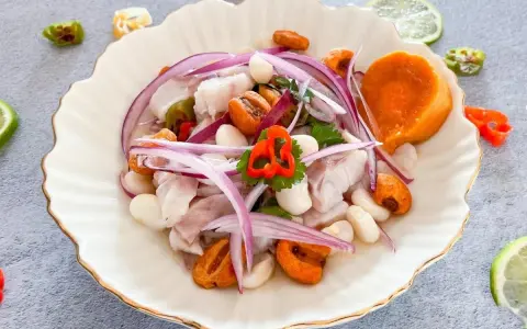 Delicioso ceviche de lubina con camote, choclo, cebolla roja y ají. Frescura y sabor en cada bocado.