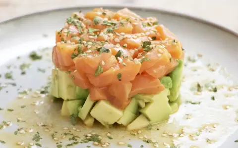 Delicioso tartar de salmón y aguacate, coronado con semillas de sésamo y perejil fresco.