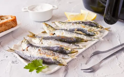 Sardinas en freidora de aire, doradas y crujientes, listas para disfrutar con limón y pan.
