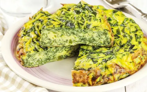 Tortilla de espinacas y queso, dorada y esponjosa, servida en un plato.