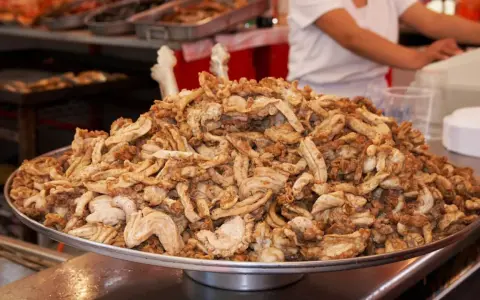 Montón de gallinejas y entresijos fritos, listos para servir en un puesto de comida callejera.