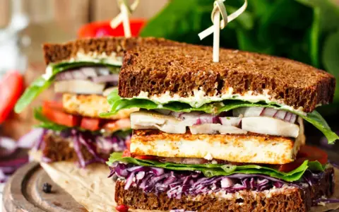 Delicioso sandwich vegetal con pan integral, tofu a la plancha, lechuga, tomate, cebolla morada y col lombarda.
