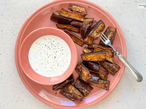 Berenjenas en freidora de aire, doradas y crujientes, servidas con una cremosa salsa blanca. ¡Un aperitivo delicioso!