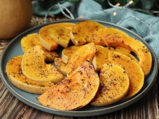 Rodajas de calabaza a la plancha, doradas y sazonadas con hierbas, servidas en un plato azul.