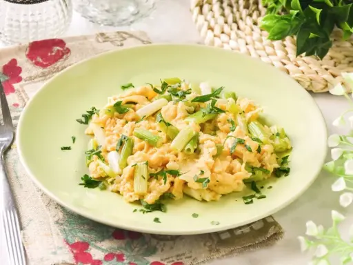 Revuelto de ajetes con perejil fresco, servido en un plato verde claro.