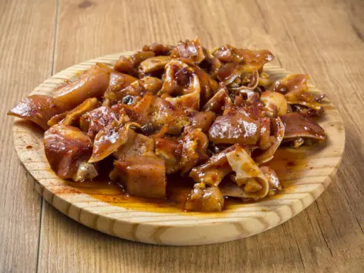 Oreja a la gallega, trozos de oreja de cerdo marinados y cocinados, servidos en una tabla de madera.