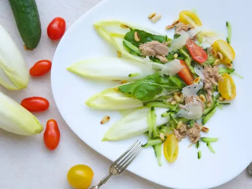 Deliciosa ensalada de endivias con atún, tomate, pepino y piñones. Un plato fresco y ligero.