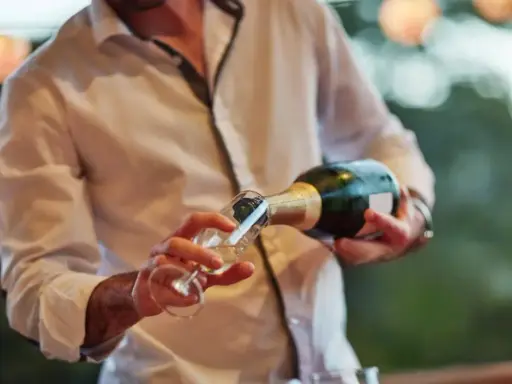 Un hombre sirve cava español en una copa.