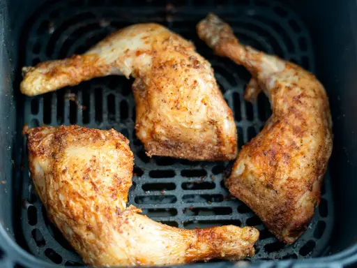 Muslos de pollo dorados y jugosos en la freidora de aire, listos para disfrutar.