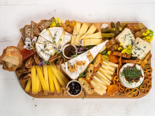 Una tabla de quesos sencilla con variedad de quesos, pan, frutas secas, uvas, pepinillos y mermelada.