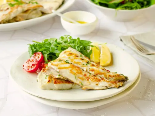 Deliciosa corvina a la plancha, servida con rúcula fresca, tomates cherry y gajos de limón. Un plato ligero y sabroso.