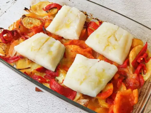 Bacalao al horno con patatas panaderas, cebolla y pimientos. Un plato casero listo para disfrutar.