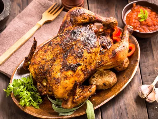 Un delicioso pollo al horno crujiente y jugoso, servido con patatas asadas, pimientos rojos y salsa. ¡Perfecto para una comida familiar!