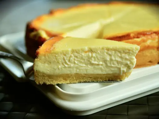 Una rebanada cremosa de tarta de queso Philadelphia, con su base dorada y relleno suave, lista para ser disfrutada.