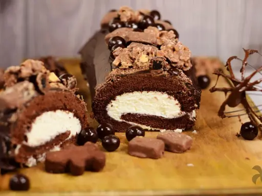 Delicioso rollo de chocolate cubierto con crema y decorado con más chocolate y dulces.