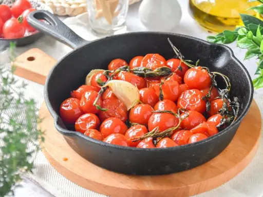 Tomates cherry confitados en sartén de hierro fundido, con ajo y hierbas aromáticas.