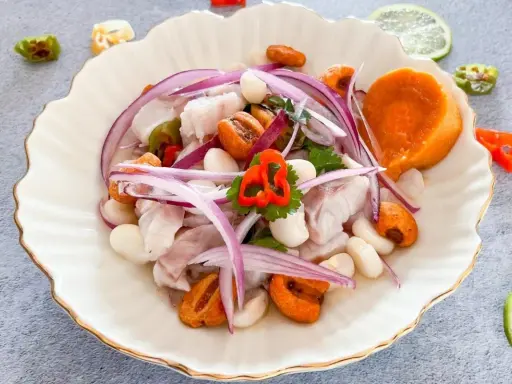 Delicioso ceviche de lubina con camote, choclo, cebolla roja y ají. Frescura y sabor en cada bocado.