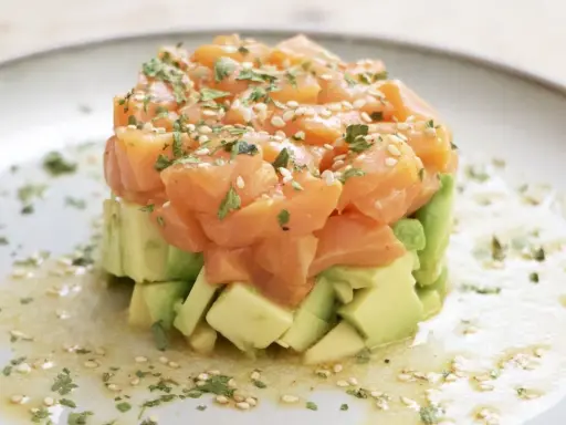 Delicioso tartar de salmón y aguacate, coronado con semillas de sésamo y perejil fresco.