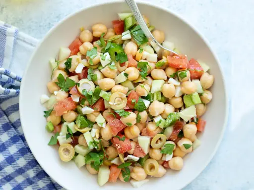 Ensalada garbanzos fresca con tomate, pepino, aceitunas y perejil. Un plato ligero y nutritivo.