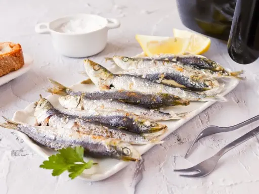 Sardinas en freidora de aire, doradas y crujientes, listas para disfrutar con limón y pan.