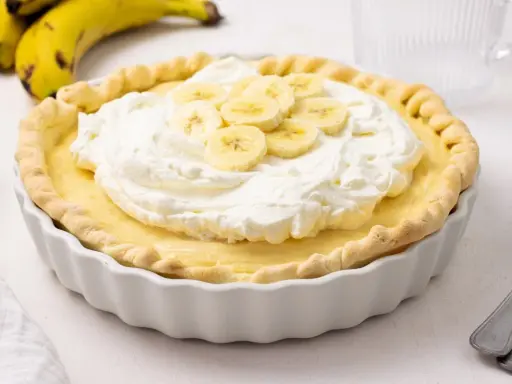 Deliciosa tarta de plátano con crema batida y rodajas de plátano fresco.