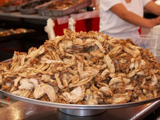 Montón de gallinejas y entresijos fritos, listos para servir en un puesto de comida callejera.