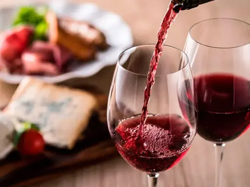 Vino tinto servido en copas, con tabla de quesos y embutidos al fondo. Una cata para apreciar la diferencia entre tempranillo y crianza.