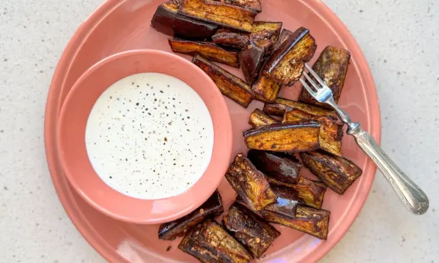 Berenjenas en freidora de aire, doradas y crujientes, servidas con una cremosa salsa blanca. ¡Un aperitivo delicioso!