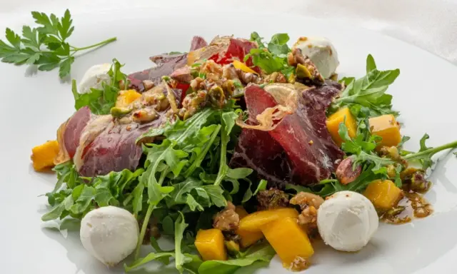 Deliciosa ensalada de cecina con mango, queso de cabra y nueces sobre rúcula fresca.